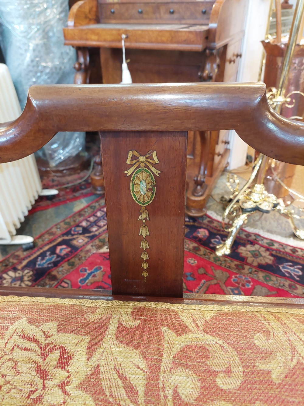 An Edwardian mahogany piano stool featuring swept armrests, an inlaid back splat, a patterned fabric seat, and geometric line inlay. View II