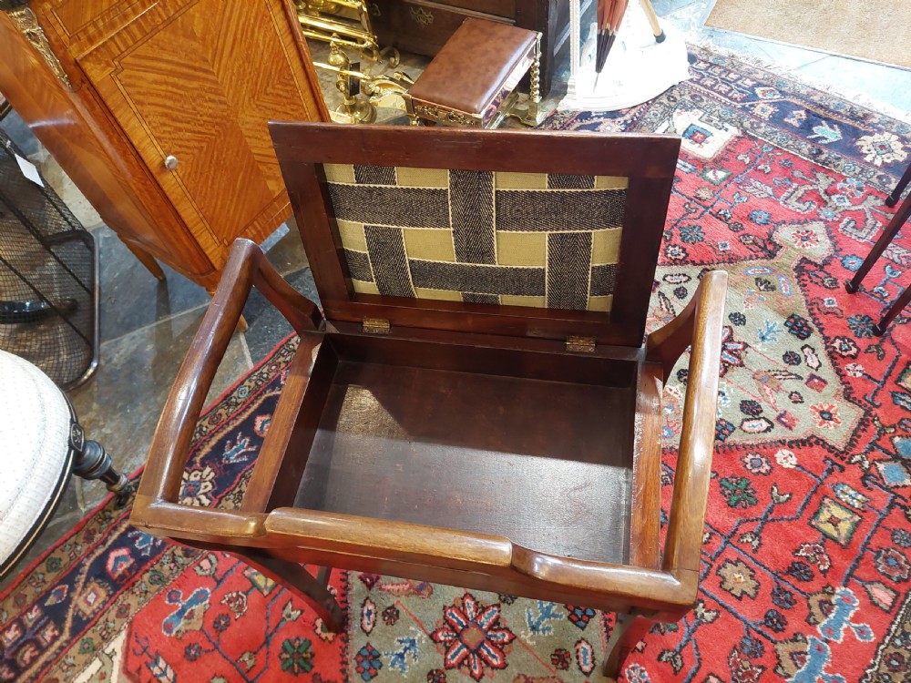 An Edwardian mahogany piano stool featuring swept armrests, an inlaid back splat, a patterned fabric seat, and geometric line inlay. View IV