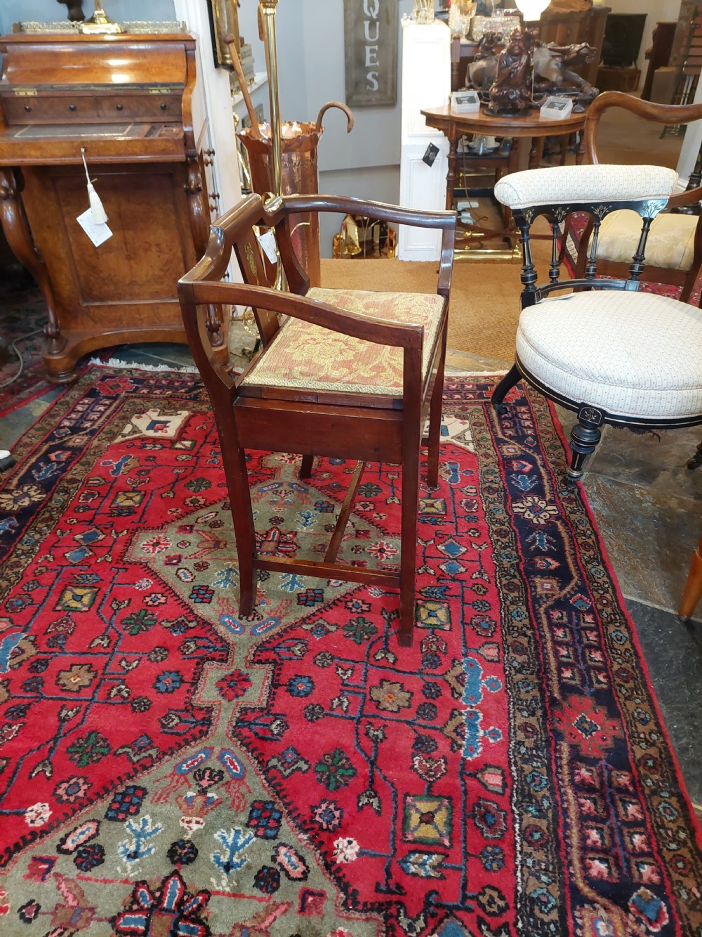 An Edwardian mahogany piano stool featuring swept armrests, an inlaid back splat, a patterned fabric seat, and geometric line inlay. View V