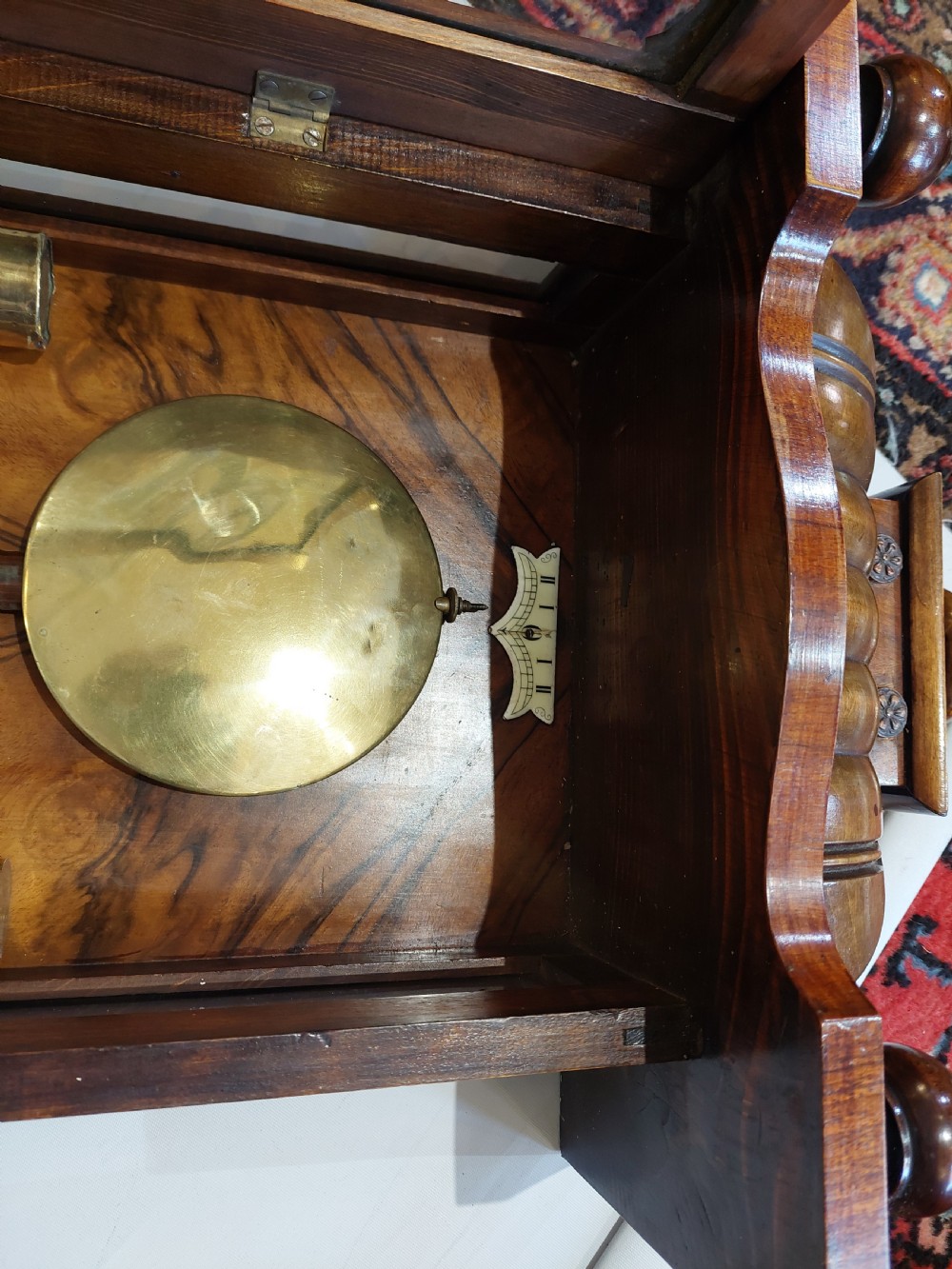 Late Victorian double weight Vienna wall clock featuring a carved walnut case topped with an eagle pediment, turned side finials, a glazed door revealing twin brass weights, and a white dial with Roman numerals. View VII