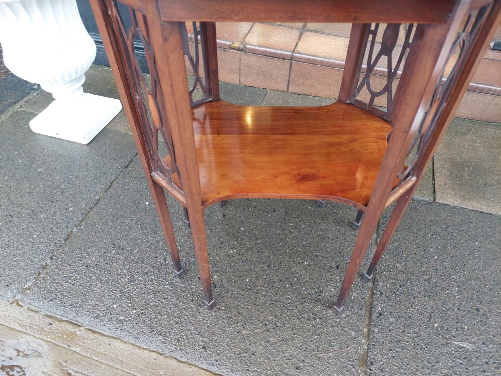 An Edwardian octagonal mahogany occasional table featuring inlaid satinwood borders, pierced side fretwork panels, and a lower tier supported by tapered square legs. View III