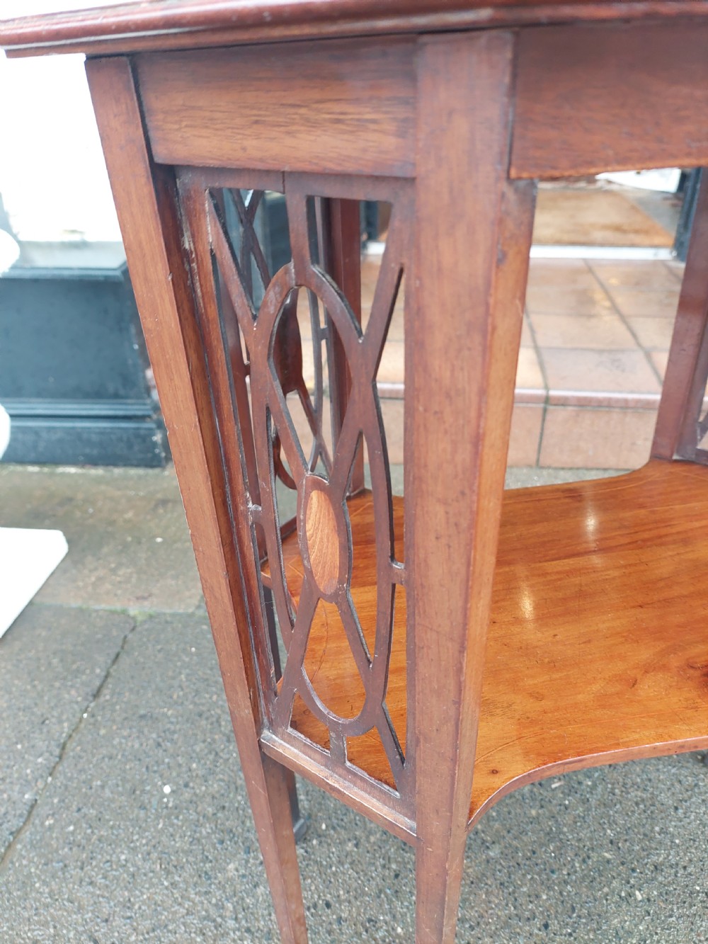 An Edwardian octagonal mahogany occasional table featuring inlaid satinwood borders, pierced side fretwork panels, and a lower tier supported by tapered square legs. View V