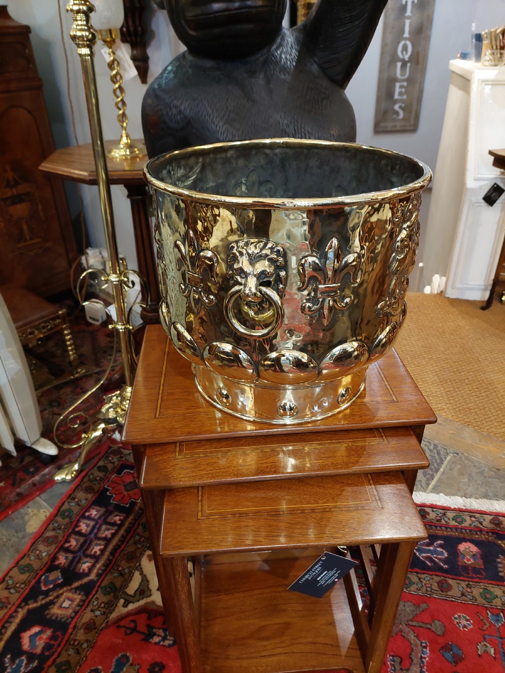 A round Victorian metal log bucket featuring embossed heraldic crests, lion mask ring handles, and gadrooned relief work. View V