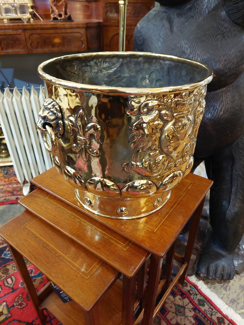 A round Victorian metal log bucket featuring embossed heraldic crests, lion mask ring handles, and gadrooned relief work. View VII