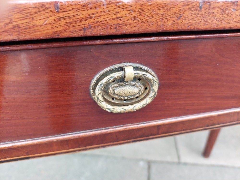 A Georgian mahogany hall table with a rounded bowfront top, a single central drawer with brass handle, a brass finial gallery rail, and four square tapered legs. View VI