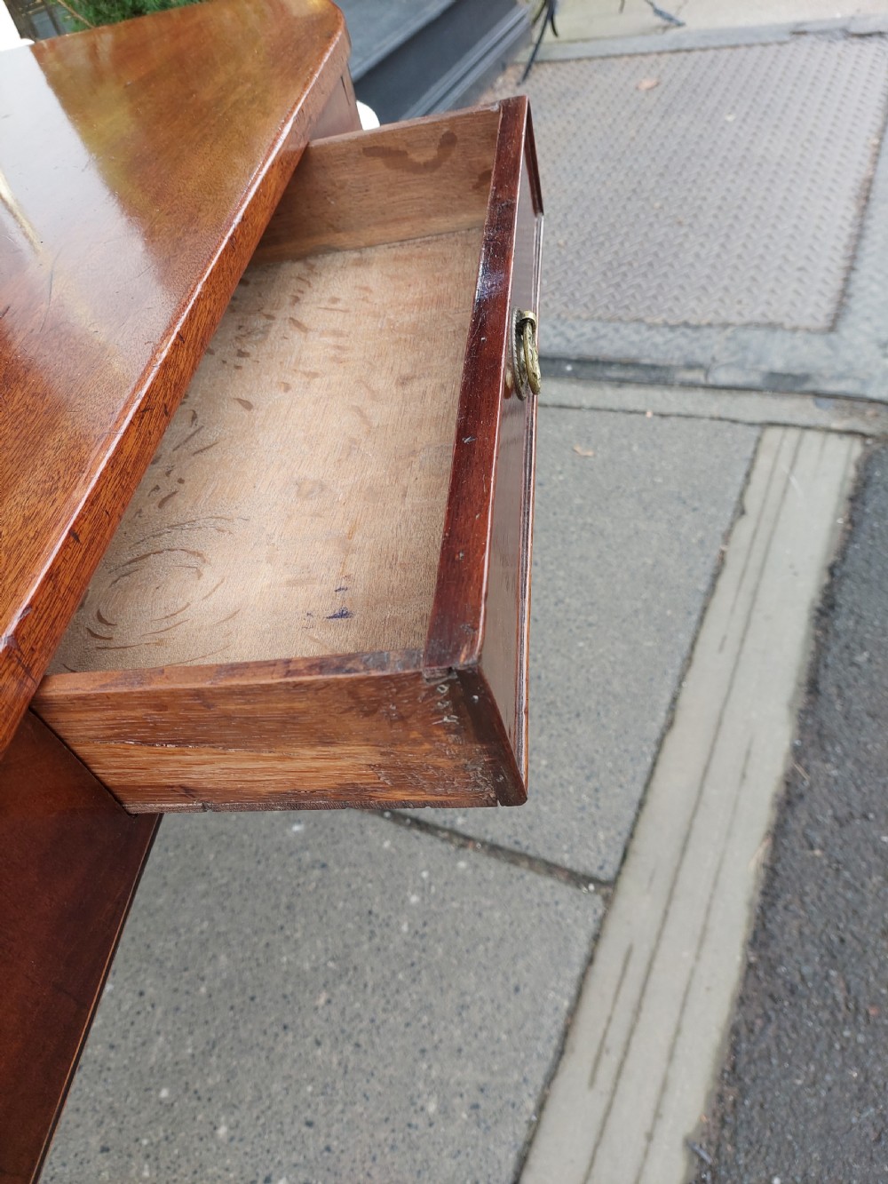 A Georgian mahogany hall table with a rounded bowfront top, a single central drawer with brass handle, a brass finial gallery rail, and four square tapered legs. View VII