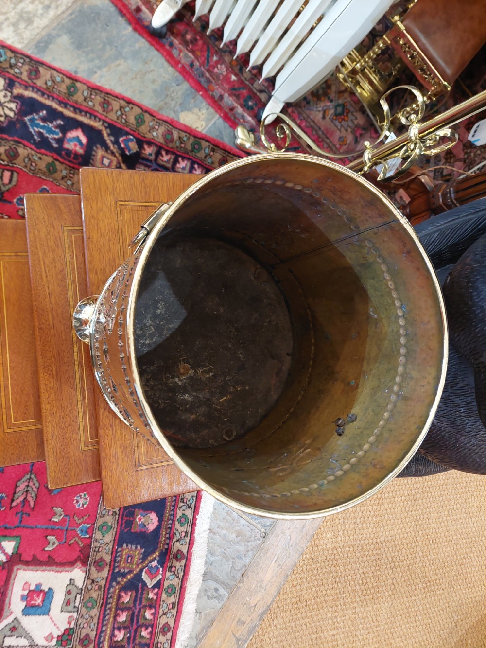 A cylindrical Victorian brass coal receiver featuring embossed garland motifs, beaded horizontal bands, side ring handles, and a fitted domed lid with a finial. View VII