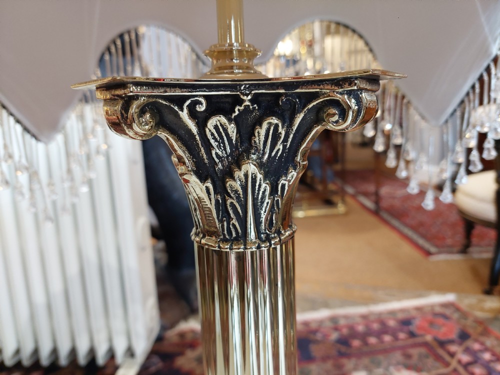 A brass column table lamp featuring a reeded stem, stepped square base, and a cream fabric dome shade trimmed with dark braid and clear glass droplet fringe. View IV