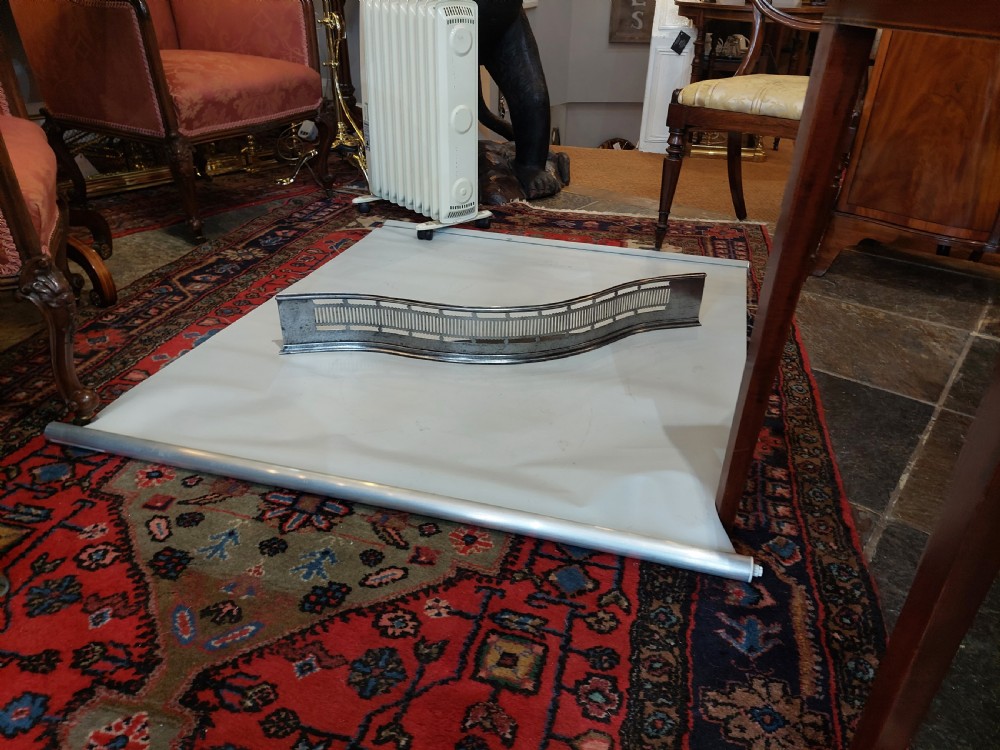A Georgian serpentine polished steel fire fender featuring pierced fretwork detail along the front curve. View II