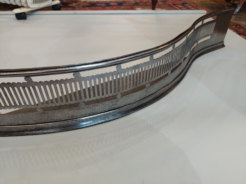 A Georgian serpentine polished steel fire fender featuring pierced fretwork detail along the front curve. View IV