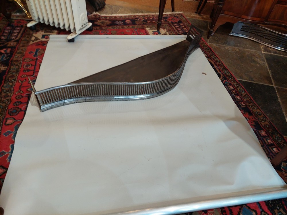 A polished steel Georgian fireplace fender featuring a serpentine front profile and vertical pierced slat fretwork. View II