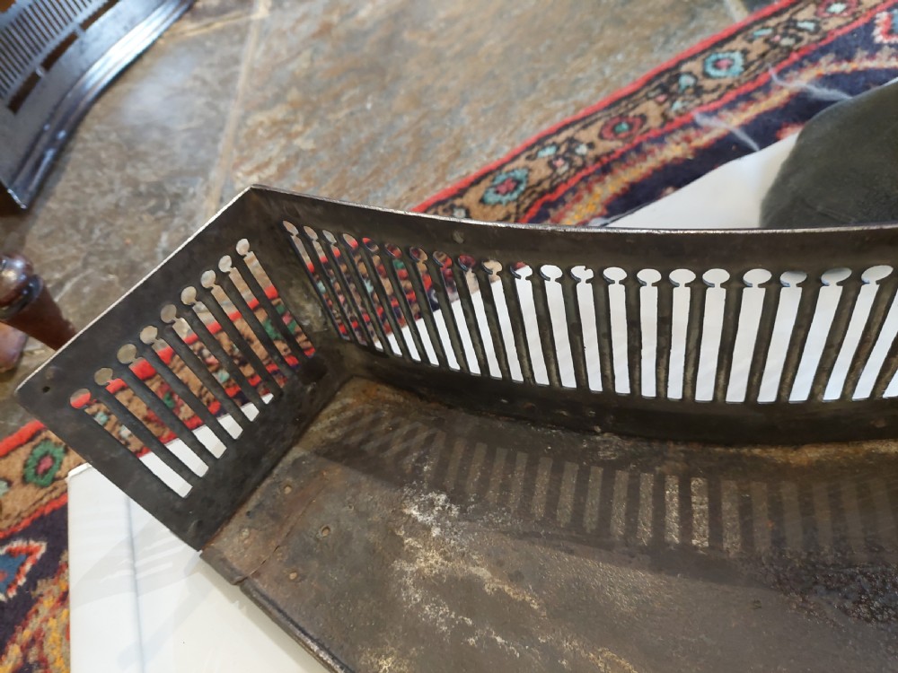 A polished steel Georgian fireplace fender featuring a serpentine front profile and vertical pierced slat fretwork. View VI