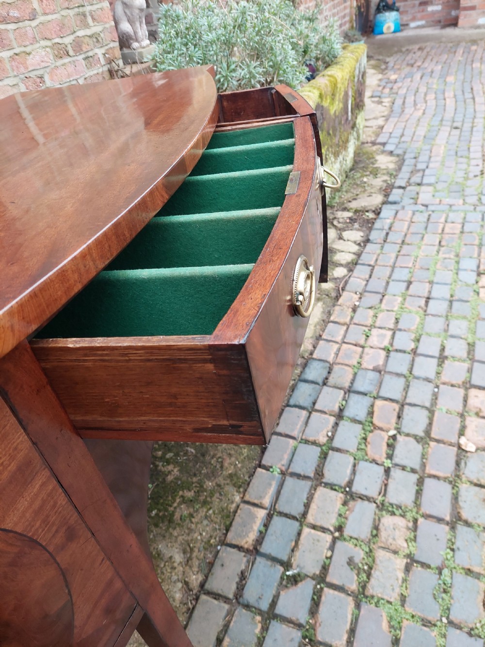 A late 18th-century mahogany bowfront sideboard featuring an arched central apron, oval-patterned veneered drawer fronts, brass drop handles, and six square tapered legs. View IX