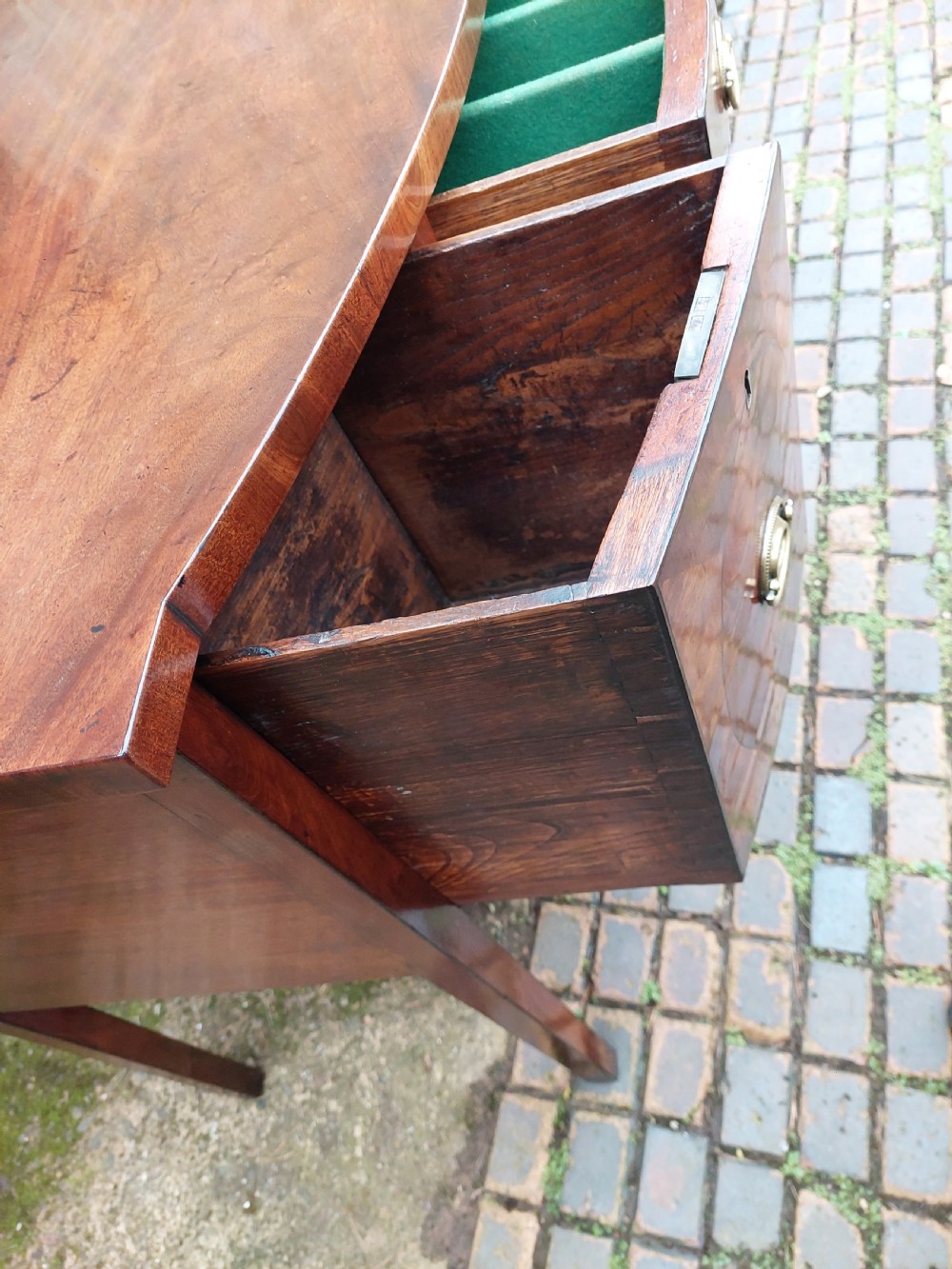 A late 18th-century mahogany bowfront sideboard featuring an arched central apron, oval-patterned veneered drawer fronts, brass drop handles, and six square tapered legs. View X