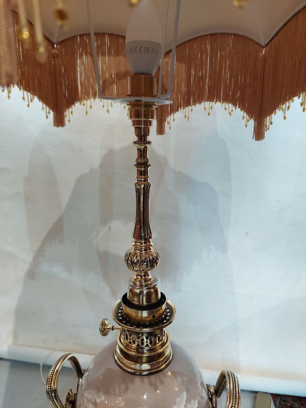 A pair of late 19th-century gilt brass and grey porcelain table lamps featuring fringed fabric lampshades. View II