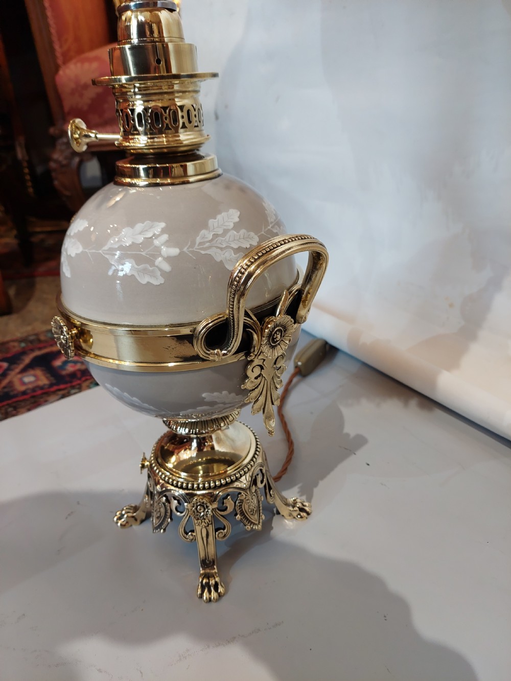 A pair of late 19th-century gilt brass and grey porcelain table lamps featuring fringed fabric lampshades. View V