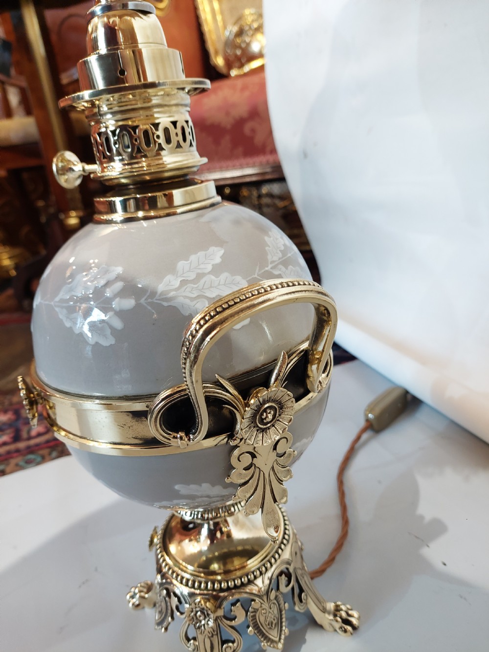 A pair of late 19th-century gilt brass and grey porcelain table lamps featuring fringed fabric lampshades. View VII