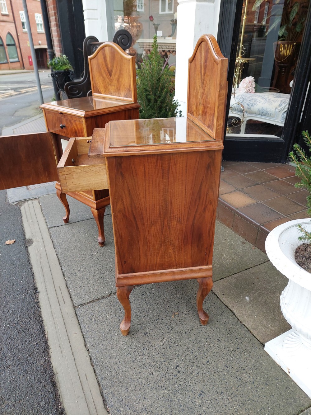 A matching pair of Art Deco figured walnut bedside cabinets with shaped upstands, single drawers, and lower cupboards on cabriole legs. View VI