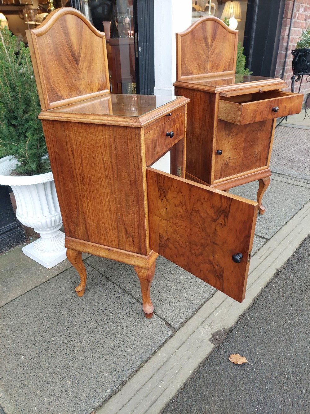 A matching pair of Art Deco figured walnut bedside cabinets with shaped upstands, single drawers, and lower cupboards on cabriole legs. View VII