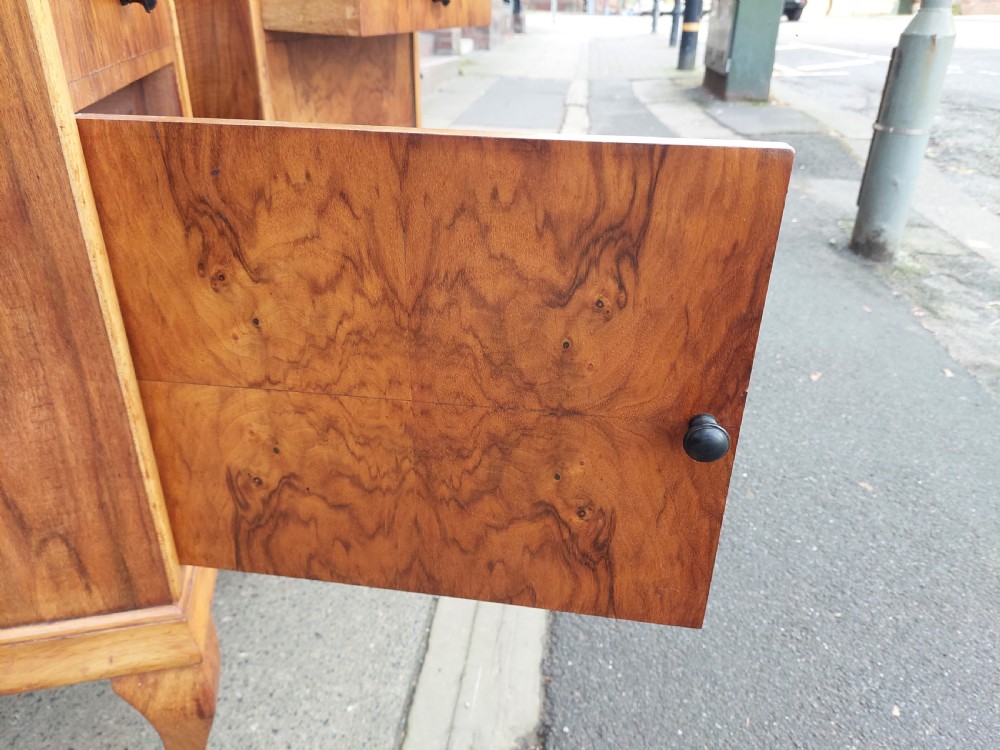 A matching pair of Art Deco figured walnut bedside cabinets with shaped upstands, single drawers, and lower cupboards on cabriole legs. View VIII