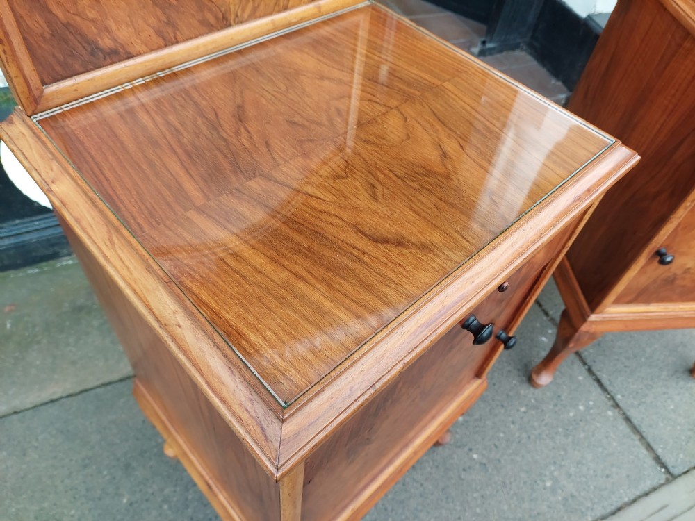 A matching pair of Art Deco figured walnut bedside cabinets with shaped upstands, single drawers, and lower cupboards on cabriole legs. View X