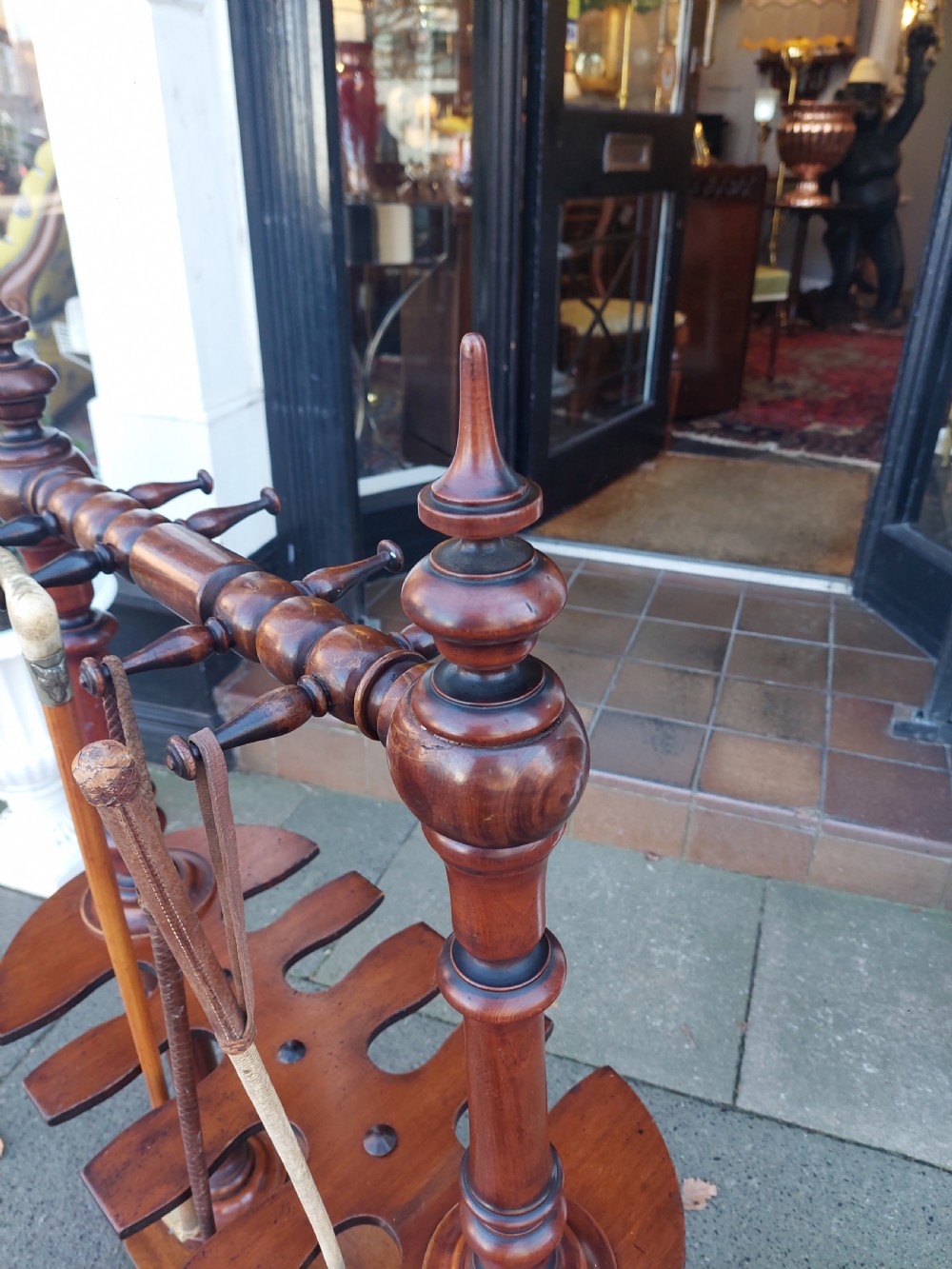 A Victorian turned mahogany whip stand featuring finial uprights, multiple upper pegs, a notched central shelf, and a solid base on feet. View IV
