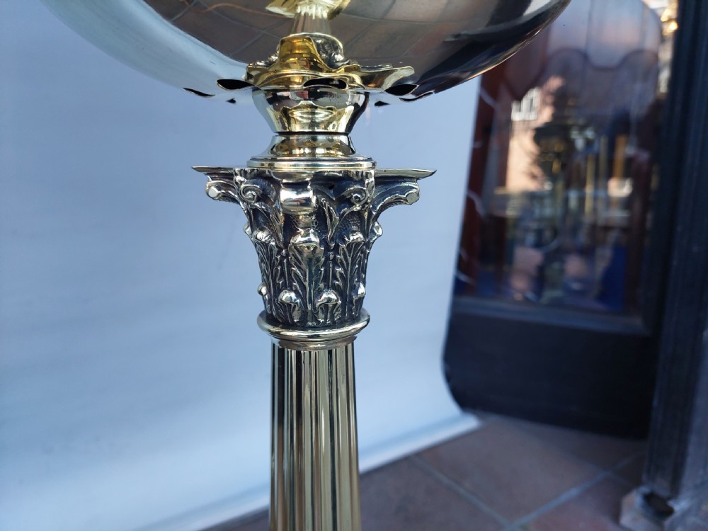 A late nineteenth-century Corinthian column oil lamp featuring a fluted stem, polished metal reservoir, and a white fabric dome shade trimmed with blue piping and long glass bead fringe. View IX