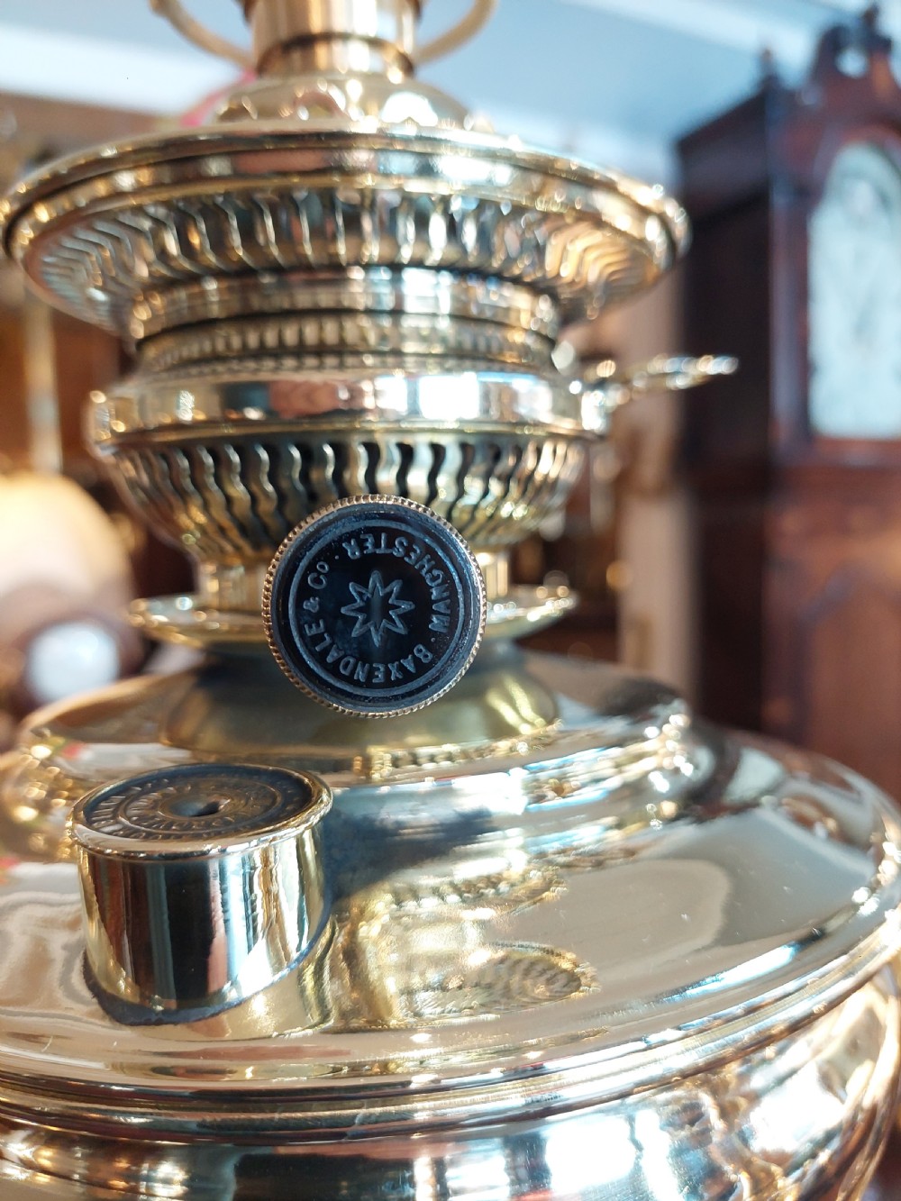 A late nineteenth-century Corinthian column oil lamp featuring a fluted stem, polished metal reservoir, and a white fabric dome shade trimmed with blue piping and long glass bead fringe. View XII