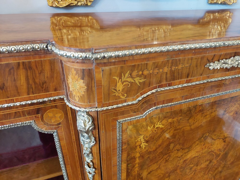 A nineteenth-century Victorian breakfront cabinet in burr walnut with marquetry inlay, gilt metal mounts, a central panelled door, and two side glazed display sections with velvet lining. View III