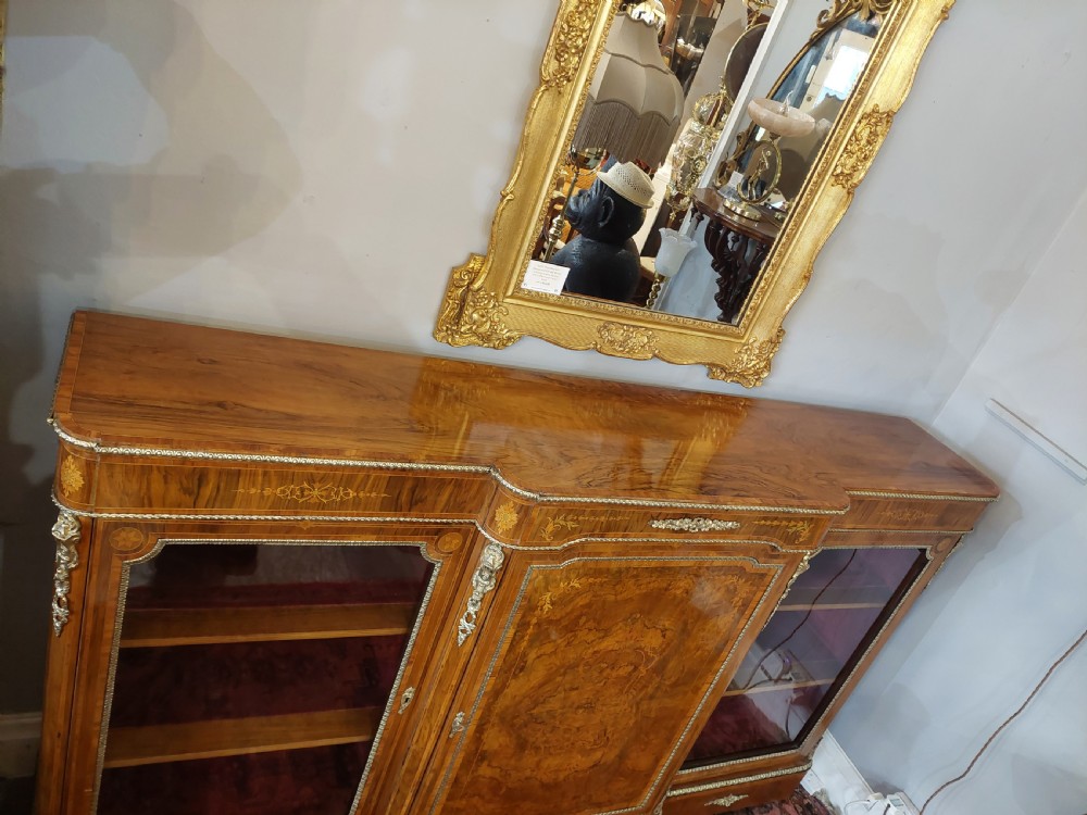 A nineteenth-century Victorian breakfront cabinet in burr walnut with marquetry inlay, gilt metal mounts, a central panelled door, and two side glazed display sections with velvet lining. View V