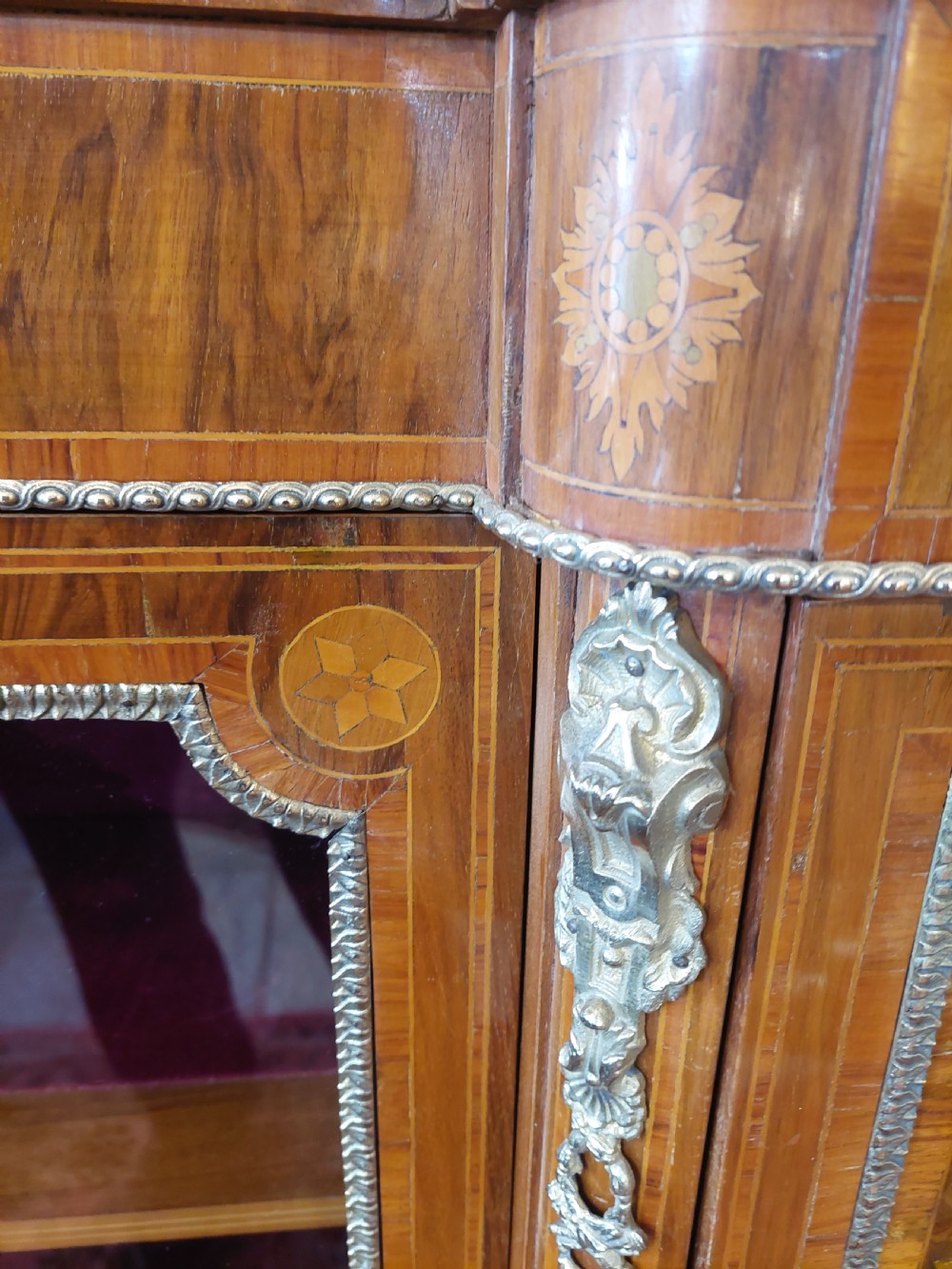 A nineteenth-century Victorian breakfront cabinet in burr walnut with marquetry inlay, gilt metal mounts, a central panelled door, and two side glazed display sections with velvet lining. View VIII