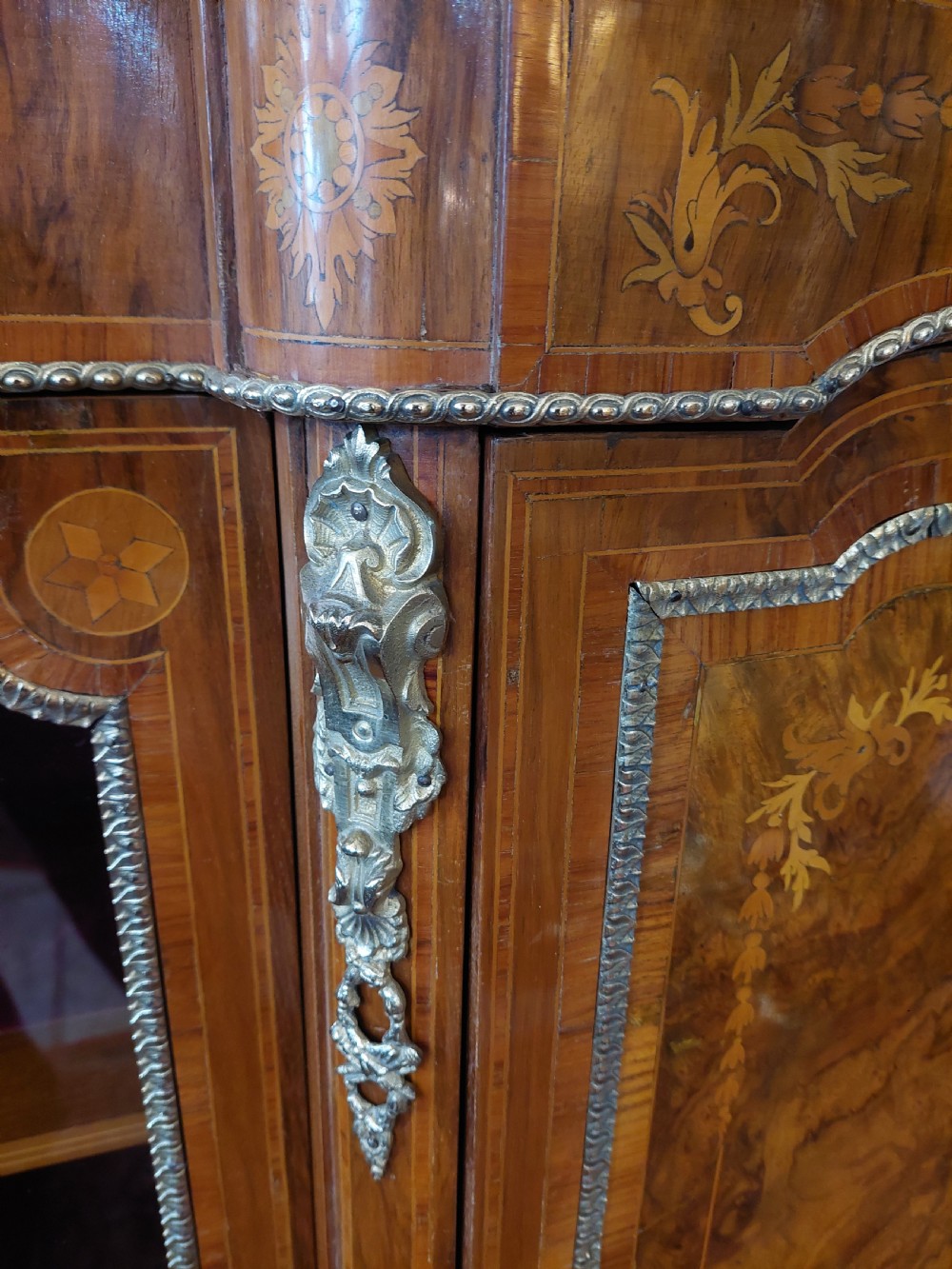 A nineteenth-century Victorian breakfront cabinet in burr walnut with marquetry inlay, gilt metal mounts, a central panelled door, and two side glazed display sections with velvet lining. View X