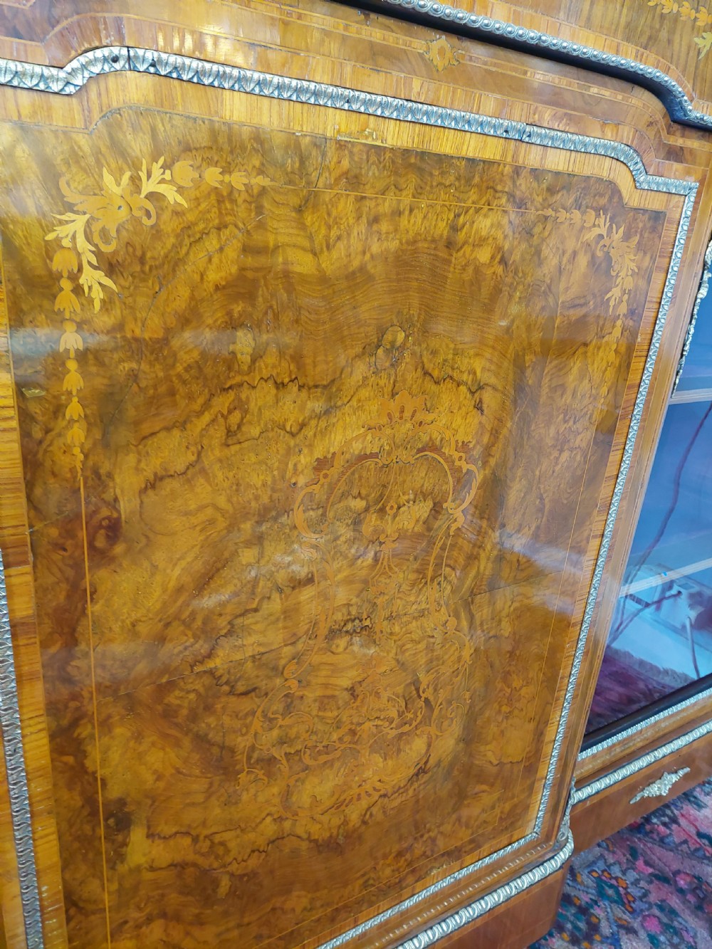 A nineteenth-century Victorian breakfront cabinet in burr walnut with marquetry inlay, gilt metal mounts, a central panelled door, and two side glazed display sections with velvet lining. View XII