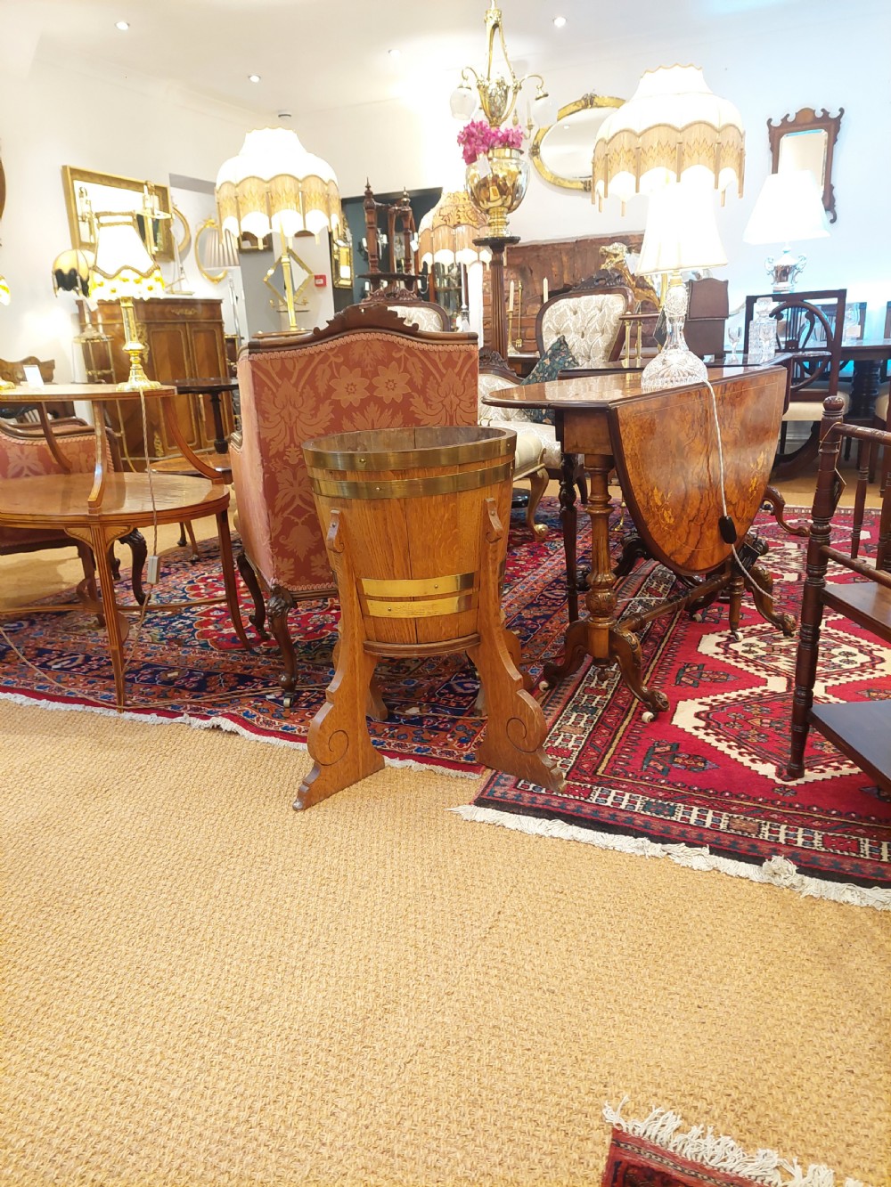 An Arts and Crafts oak planter featuring coopered wood staves secured with broad brass bands, supported on three carved scrolled timber legs. View III