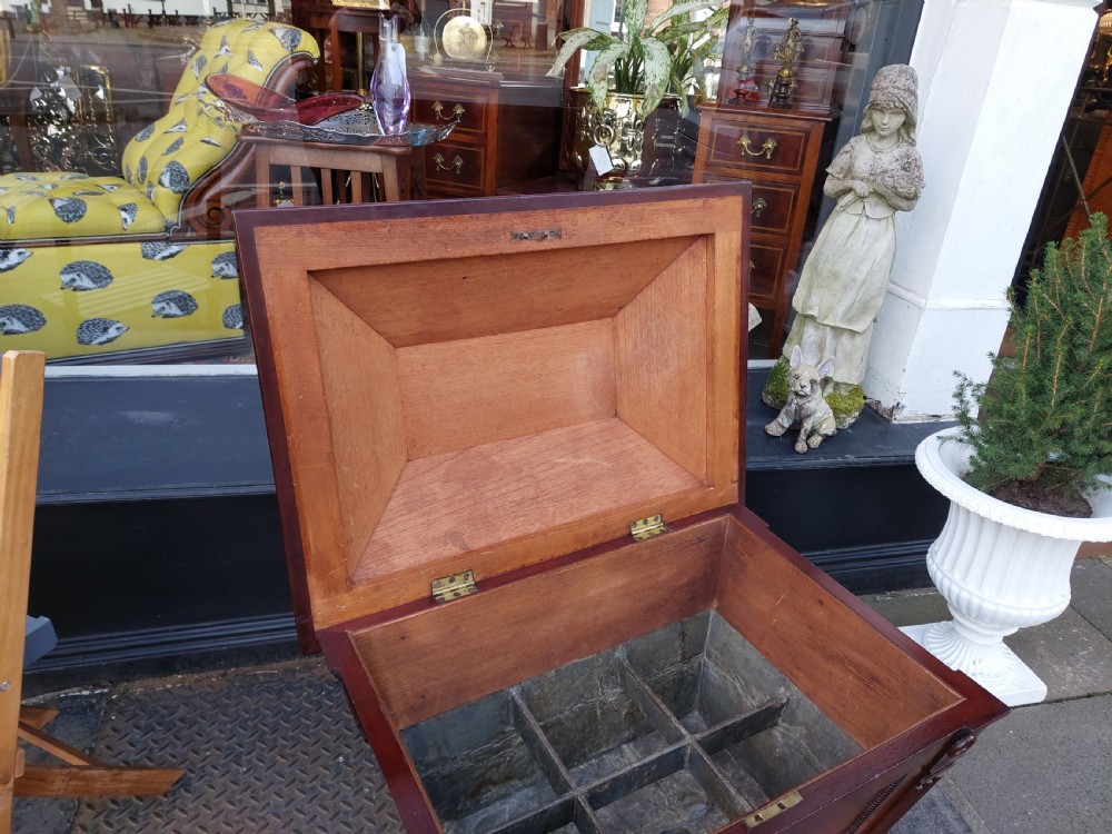 A late Regency flame mahogany sarcophagus cellarette featuring a faceted hinged lid, carved lion paw feet, and beaded edge moulding. View IV