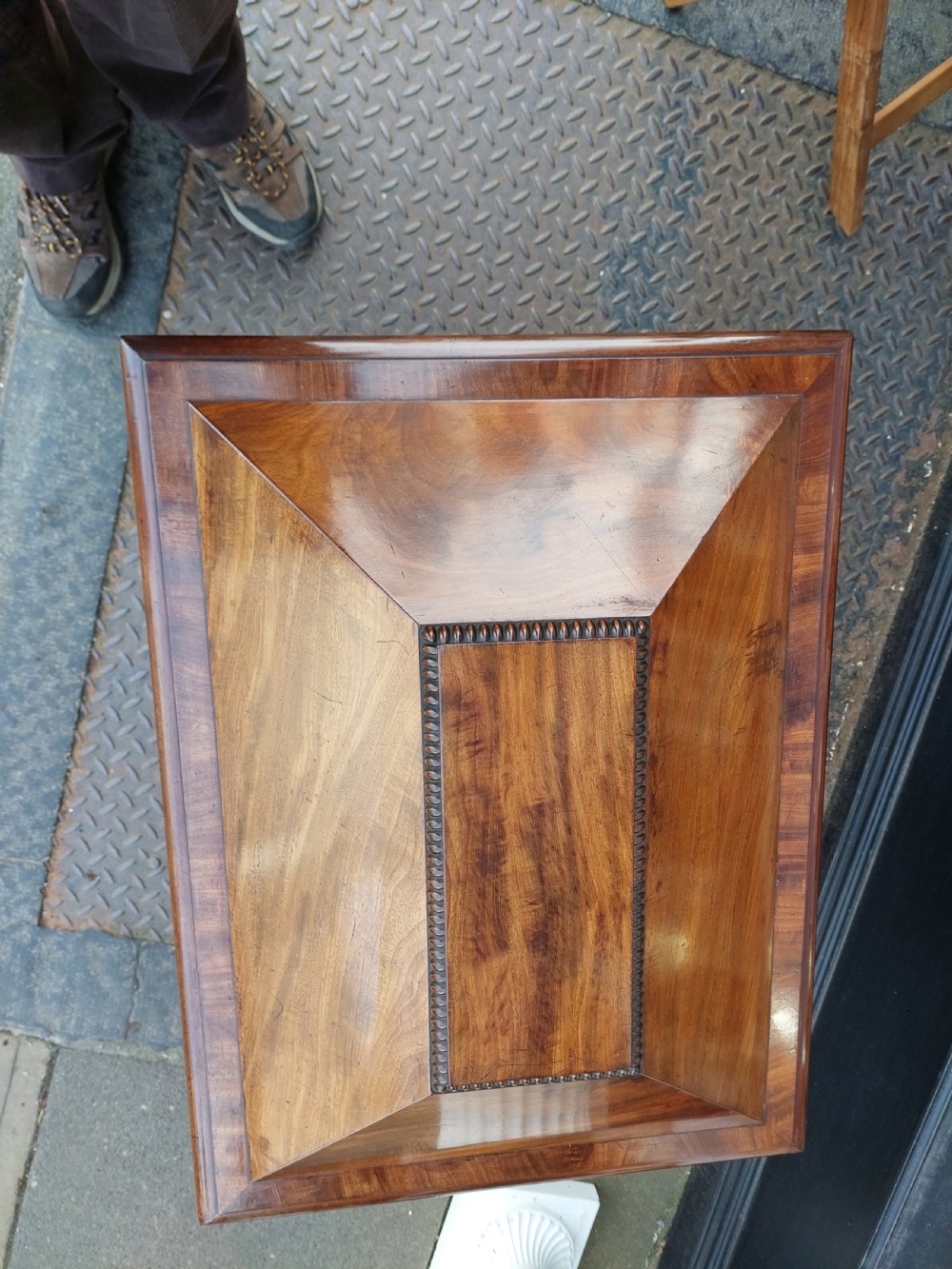 A late Regency flame mahogany sarcophagus cellarette featuring a faceted hinged lid, carved lion paw feet, and beaded edge moulding. View VII