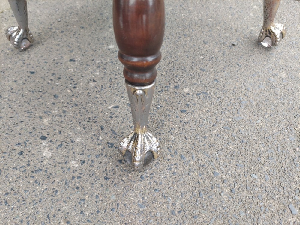 An early 20th-century dark mahogany piano stool featuring a circular swivel top, turned spindled legs, central pillar, and metal claw feet with glass balls. View IV