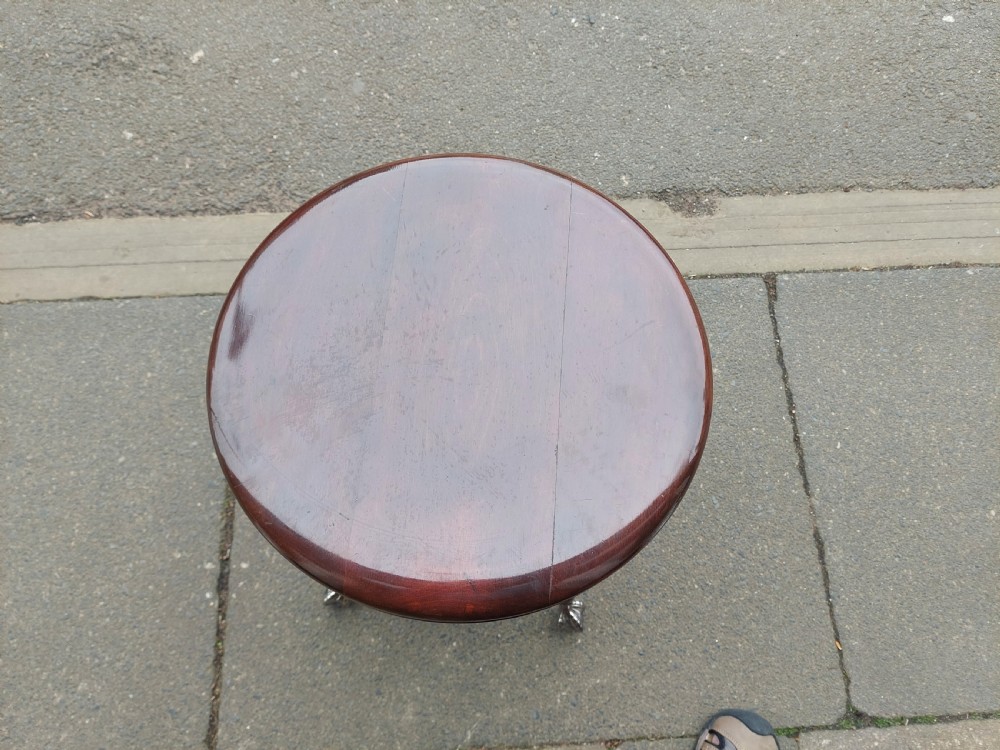 An early 20th-century dark mahogany piano stool featuring a circular swivel top, turned spindled legs, central pillar, and metal claw feet with glass balls. View V