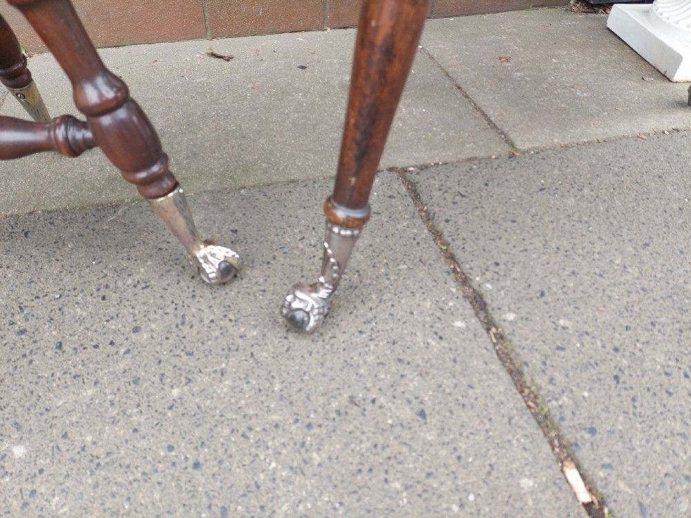 An early 20th-century dark mahogany piano stool featuring a circular swivel top, turned spindled legs, central pillar, and metal claw feet with glass balls. View VII