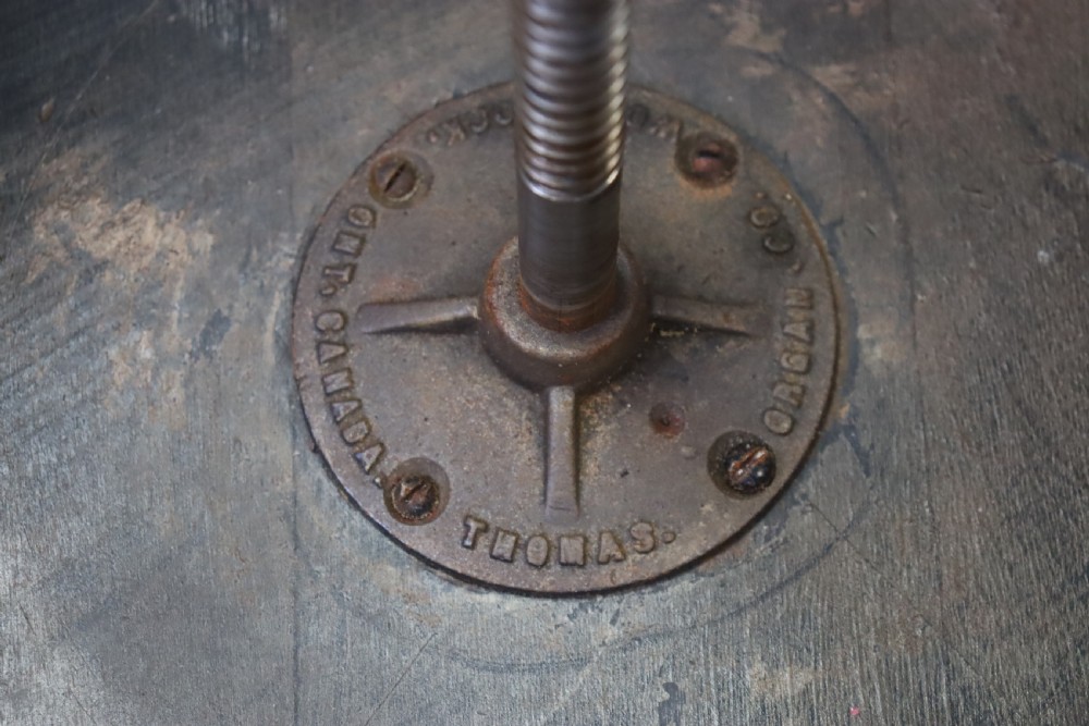 An early 20th-century dark mahogany piano stool featuring a circular swivel top, turned spindled legs, central pillar, and metal claw feet with glass balls. View XI