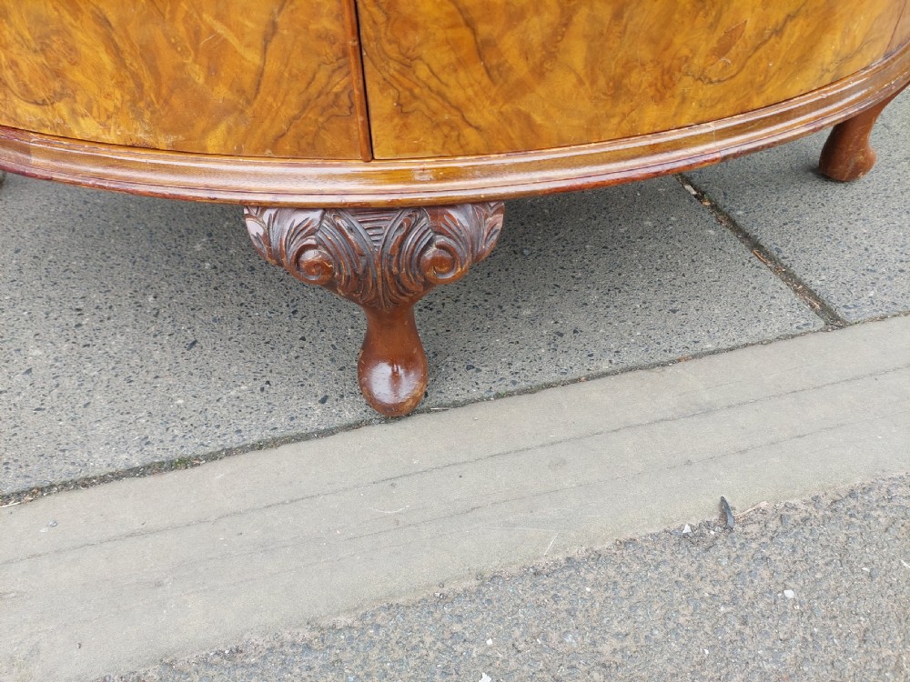 An early twentieth-century demi-lune drinks cabinet crafted from golden burr walnut veneer with carved cabriole legs and brass hardware. View II