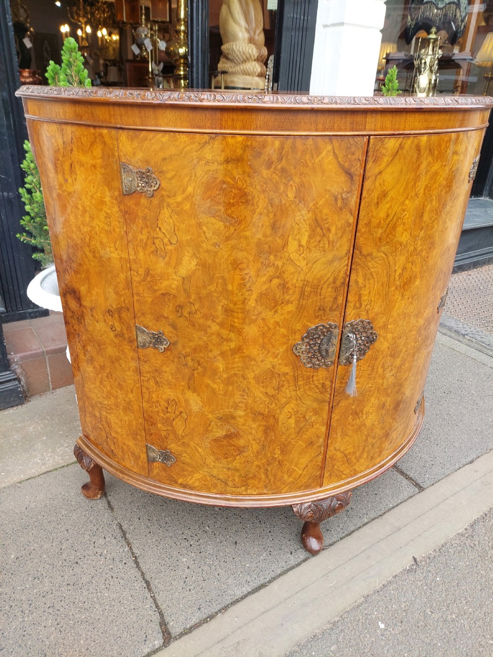 An early twentieth-century demi-lune drinks cabinet crafted from golden burr walnut veneer with carved cabriole legs and brass hardware. View VIII