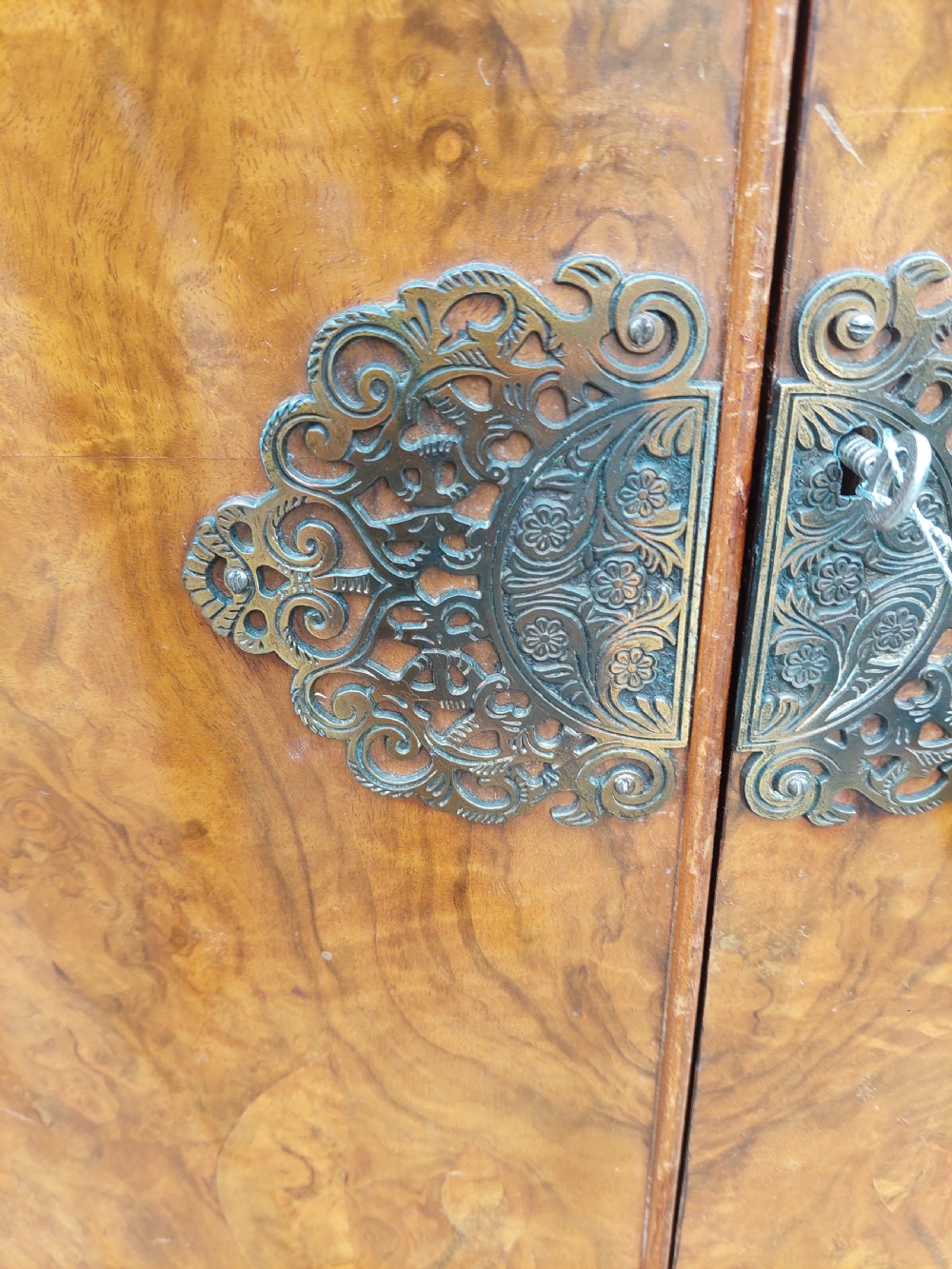 An early twentieth-century demi-lune drinks cabinet crafted from golden burr walnut veneer with carved cabriole legs and brass hardware. View IX
