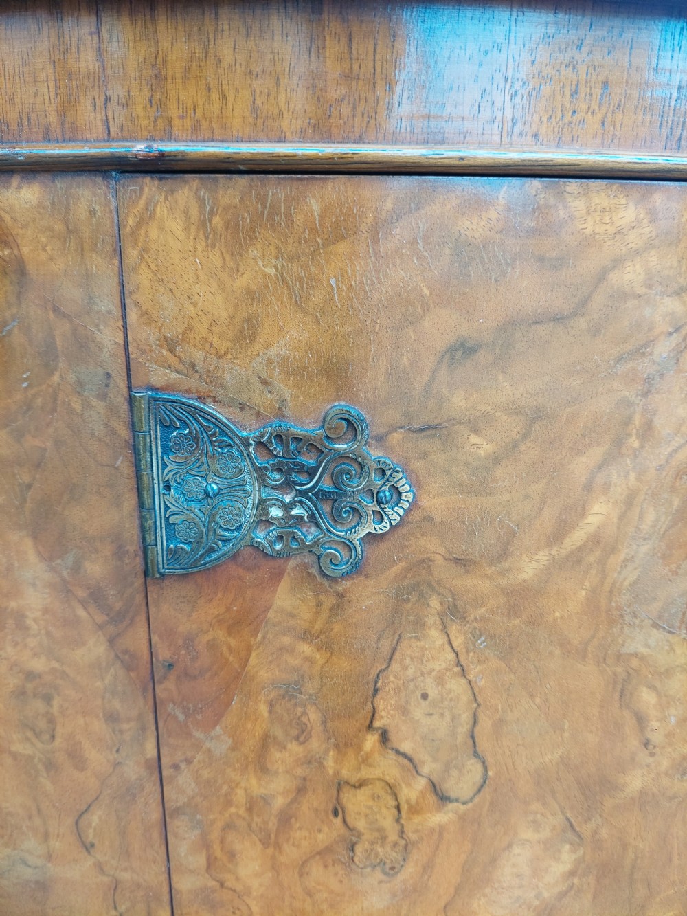 An early twentieth-century demi-lune drinks cabinet crafted from golden burr walnut veneer with carved cabriole legs and brass hardware. View X