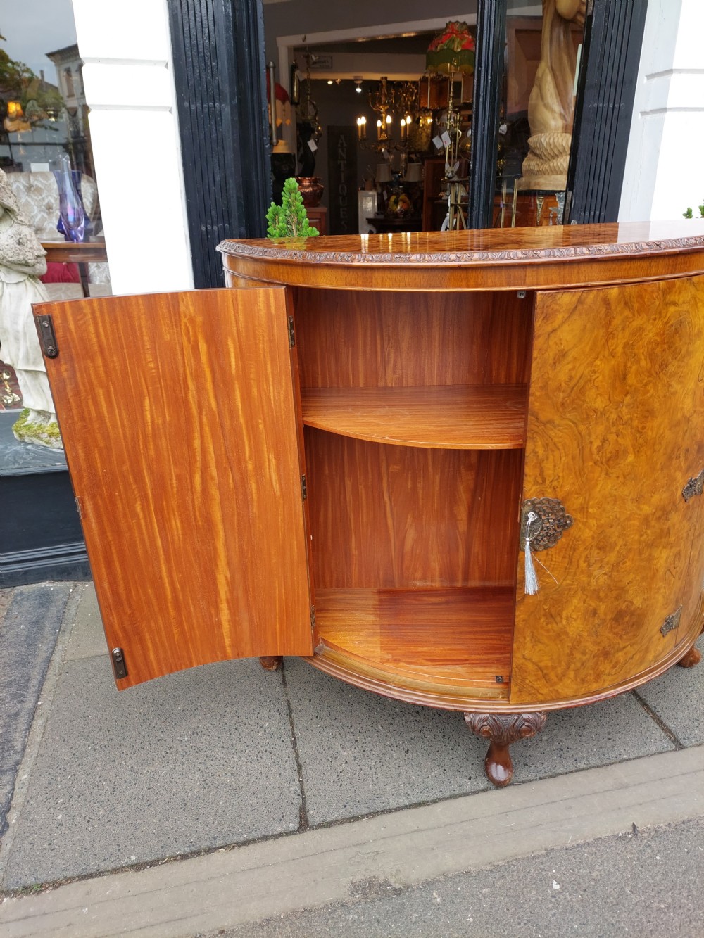An early twentieth-century demi-lune drinks cabinet crafted from golden burr walnut veneer with carved cabriole legs and brass hardware. View XI