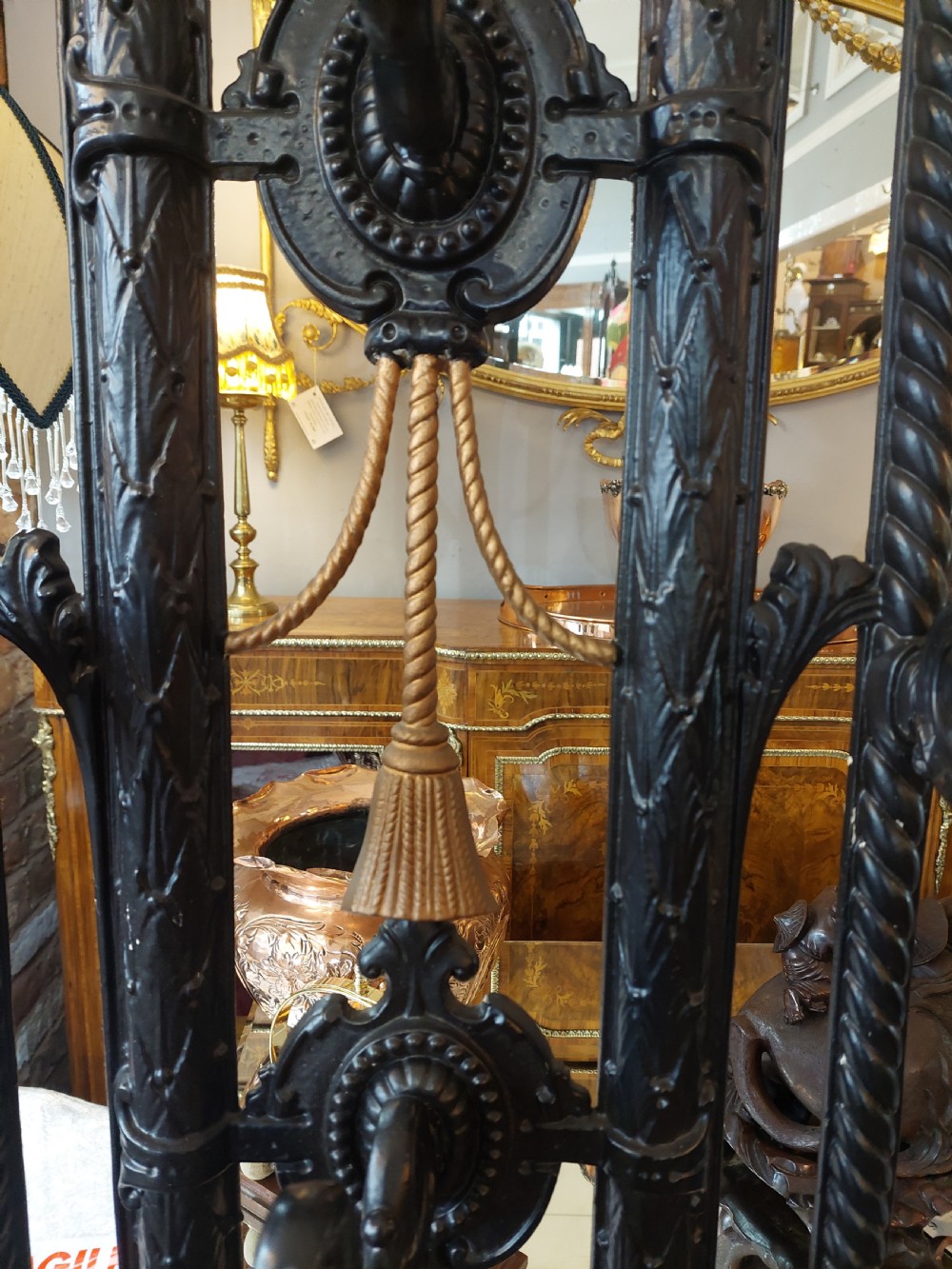 An ornate 19th-century black cast iron hall stand featuring coat hooks, intricate scrollwork, umbrella compartments, and a removable drip tray base. View VII