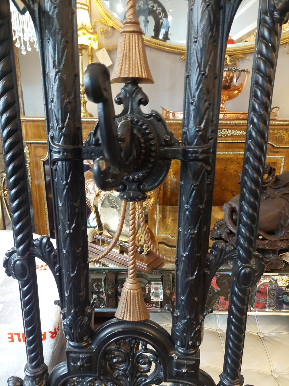 An ornate 19th-century black cast iron hall stand featuring coat hooks, intricate scrollwork, umbrella compartments, and a removable drip tray base. View VIII