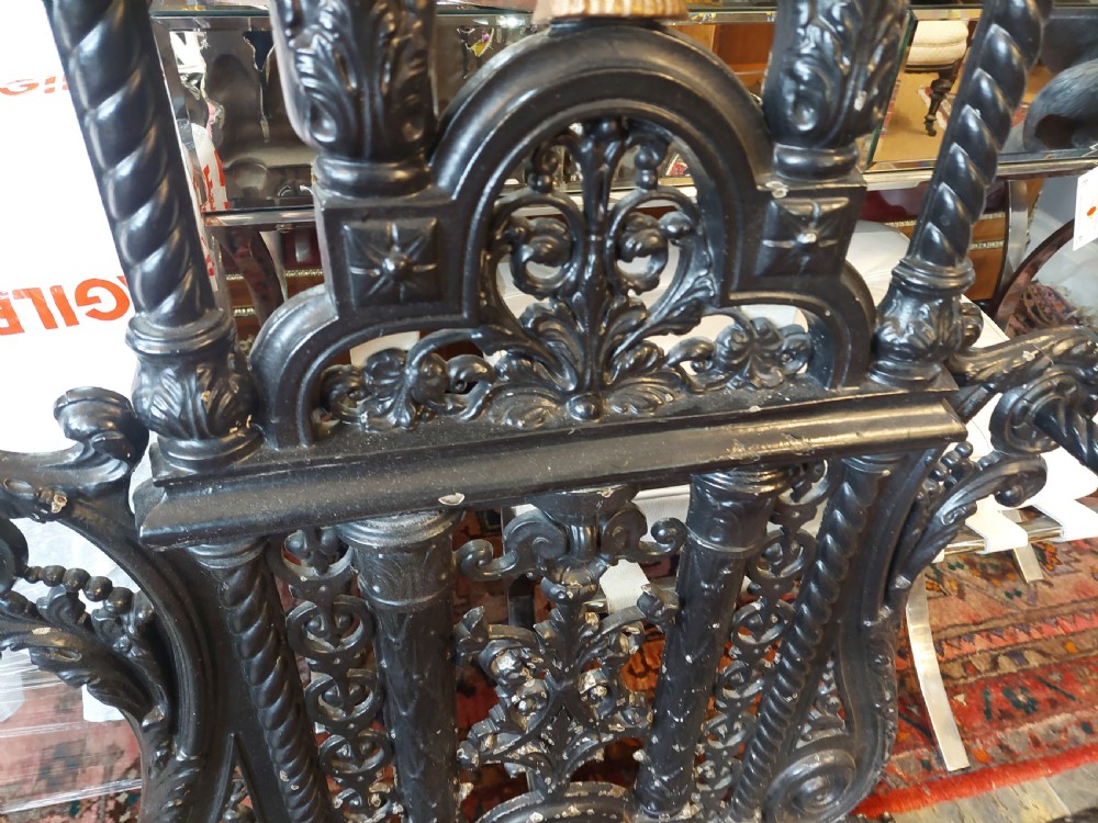 An ornate 19th-century black cast iron hall stand featuring coat hooks, intricate scrollwork, umbrella compartments, and a removable drip tray base. View IX