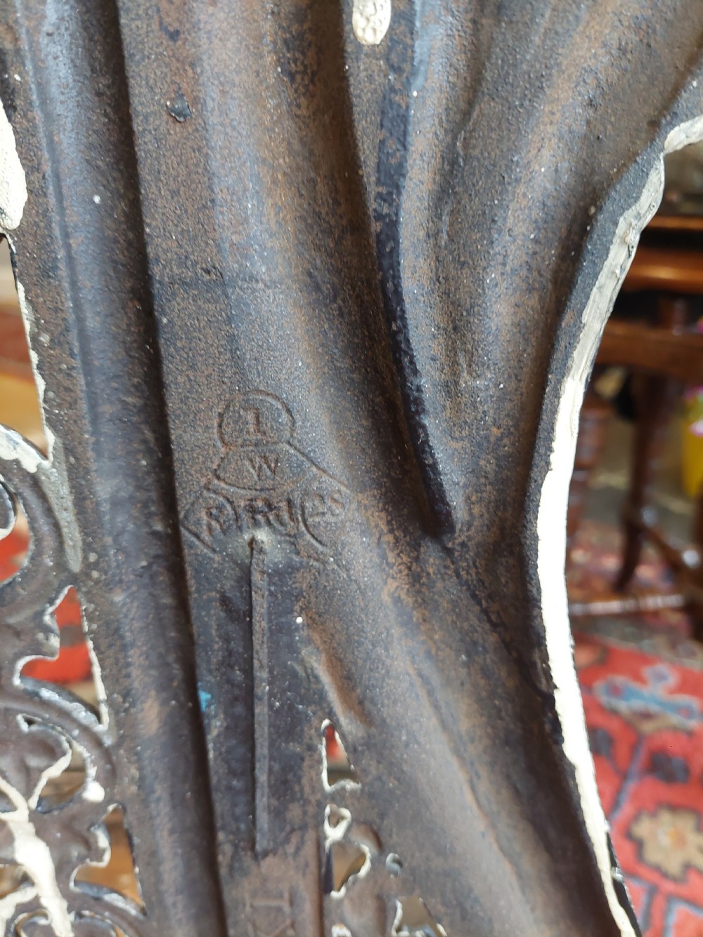 An ornate 19th-century black cast iron hall stand featuring coat hooks, intricate scrollwork, umbrella compartments, and a removable drip tray base. View XII