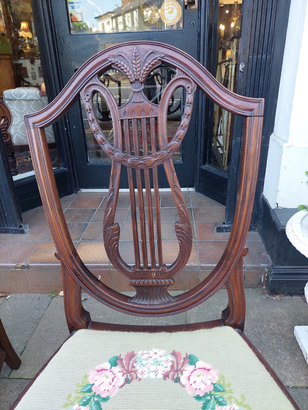 A set of six late nineteenth-century mahogany dining chairs featuring shield-shaped backs with carved lyre motifs and pale green upholstered seats. View III